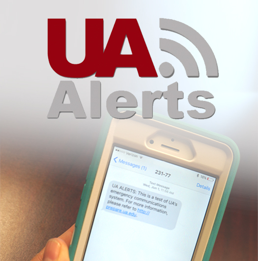 A cell phone showing a UA Alert on the screen with the words UA Alerts at the top of the photo.